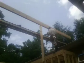 Carpenter setting a ridge beam over a new addition frame — Ice Dam Removal by Roofing Brothers in Parker City