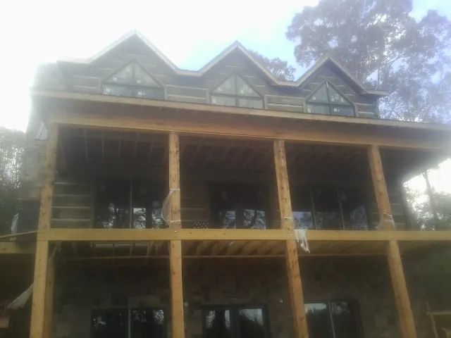 Dormers and porch framing on a large log home under construction — Roof Coating work by our crew in Parker City