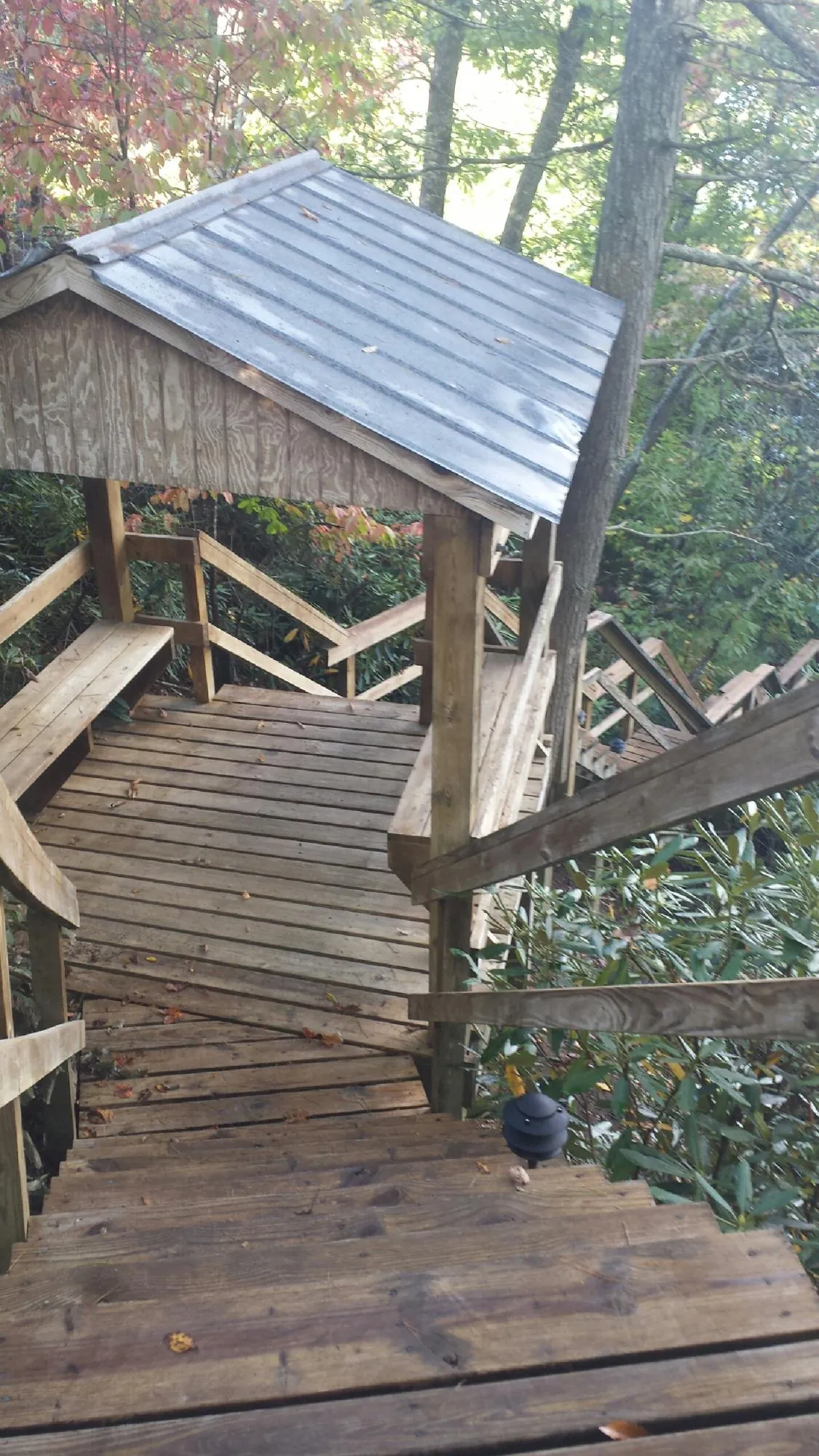 Metal roofed shelter over wooden steps on a wooded walkway — Skylight Repair & Installation work by our crew in Parker City