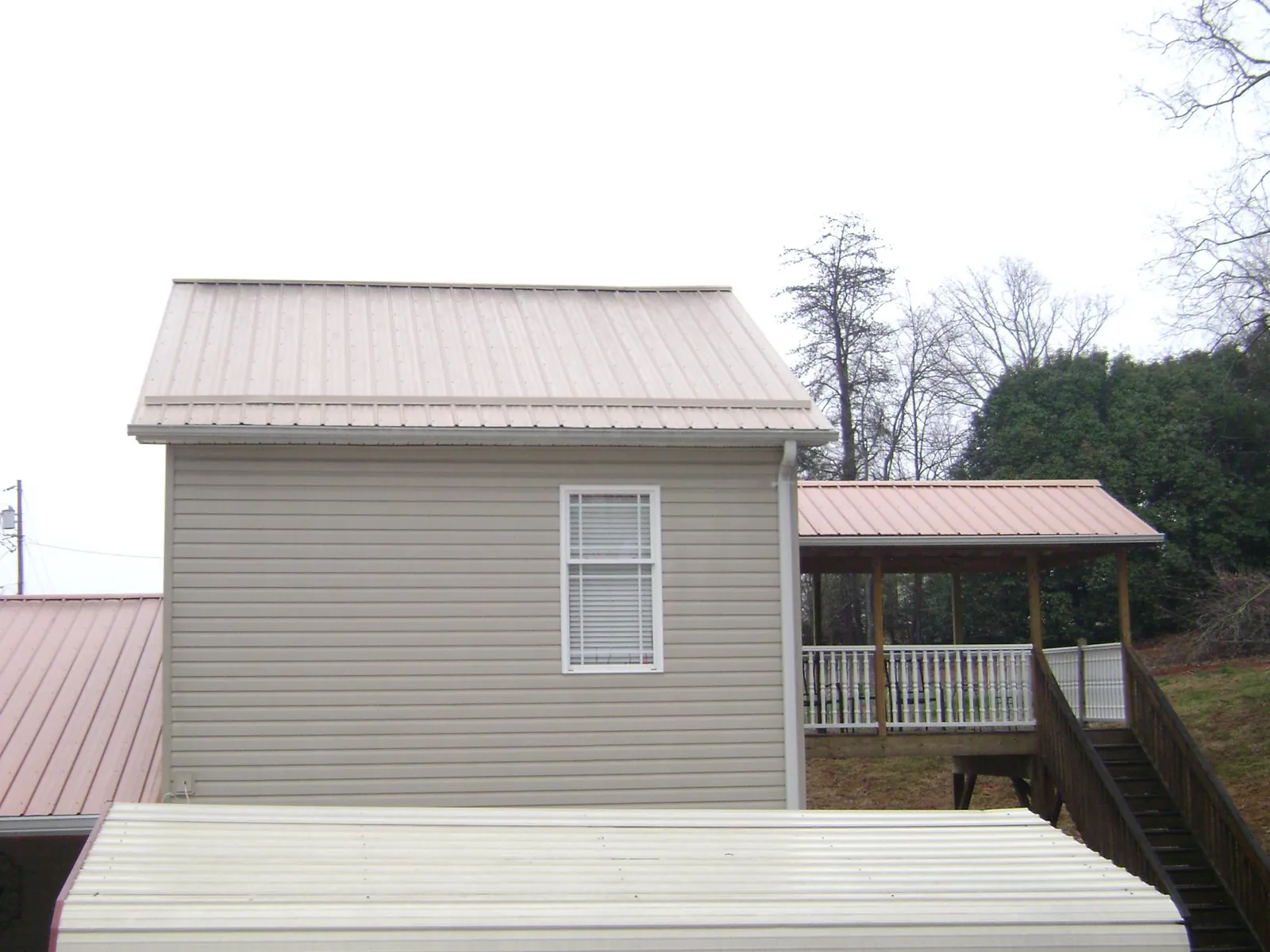 Tan metal roofs on a two story addition and attached porch, from a Roof Replacement job in Parker City