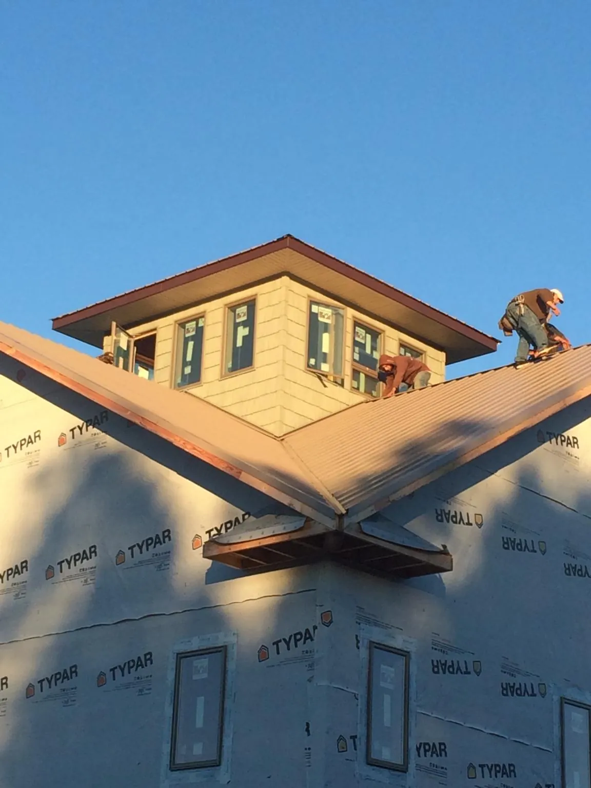 Roofers working around a rooftop cupola on a new metal roof at sunset — Roof Waterproofing in Parker City by Roofing Brothers